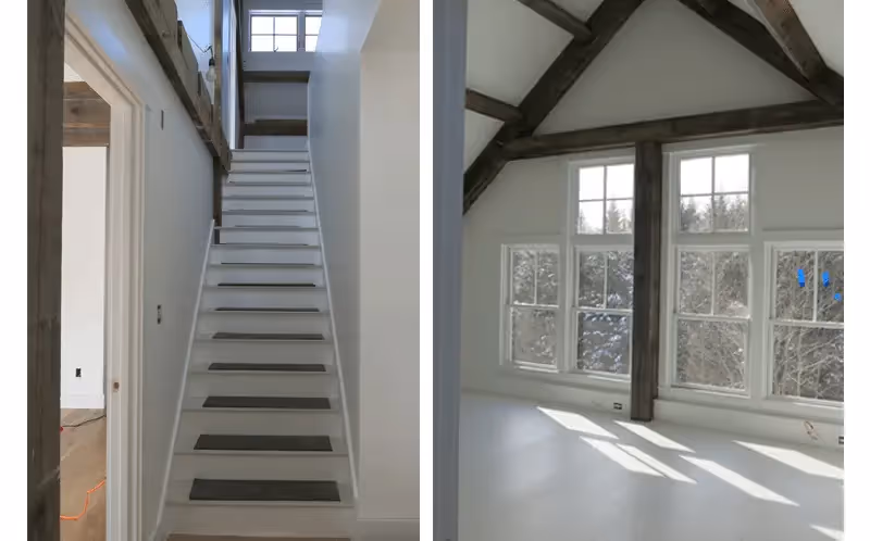 Bright interior with wooden staircase and exposed beams near large windows
