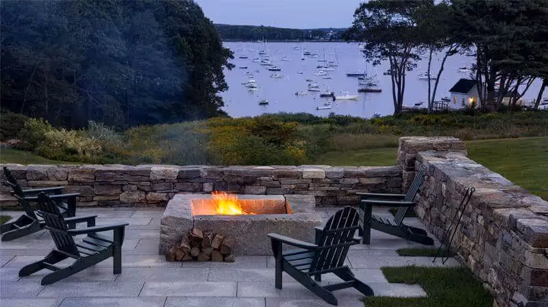 Cozy stone fire pit overlooking marina with sailboats at dusk