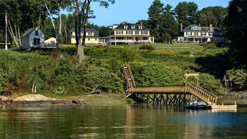 Wooden pier extends to calm lake with lakeside homes and lush green landscape