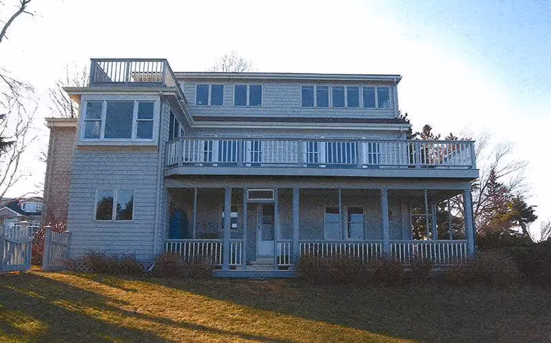 Gray two-story beach house with multiple decks and white railings