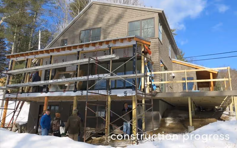 Wooden house under construction with scaffolding in snowy winter landscape