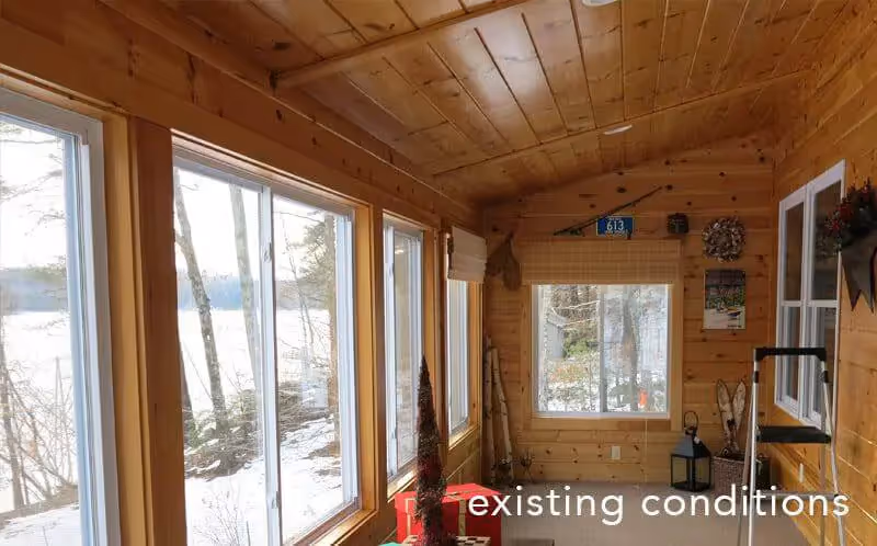 Wooden cabin interior with large windows overlooking snowy winter forest