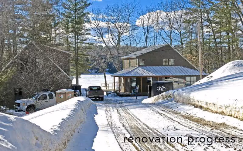 Snow-covered driveway with trucks near wooden buildings in winter