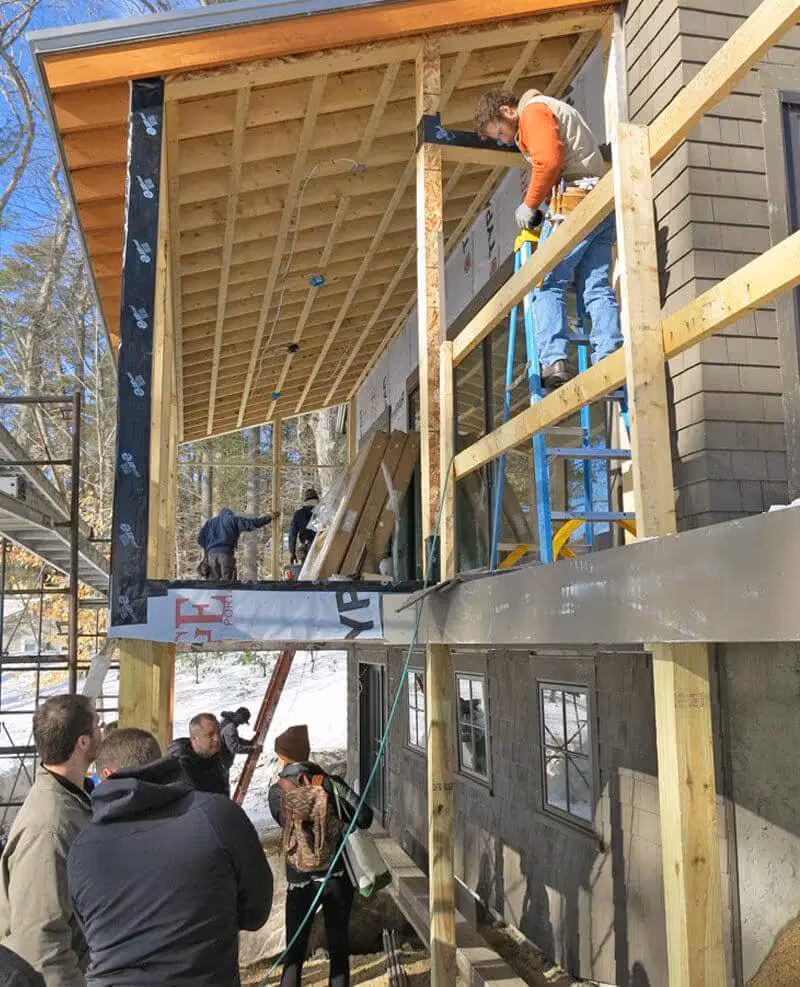 Construction workers building a wooden structure on scaffolding near trees