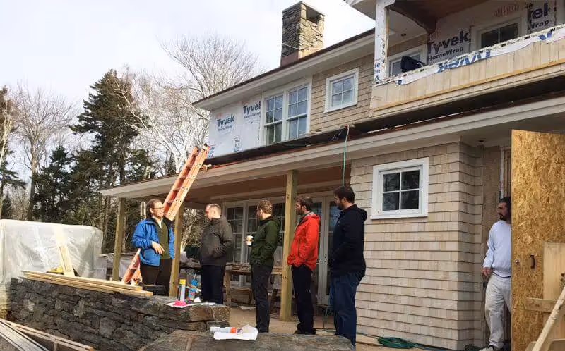 Construction crew working on house exterior during winter renovation project