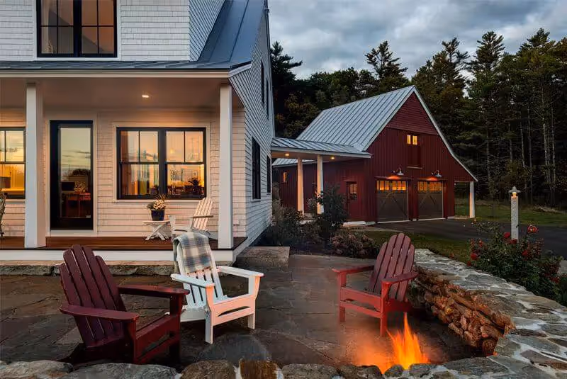 Cozy evening by fire pit with Adirondack chairs near white and red houses