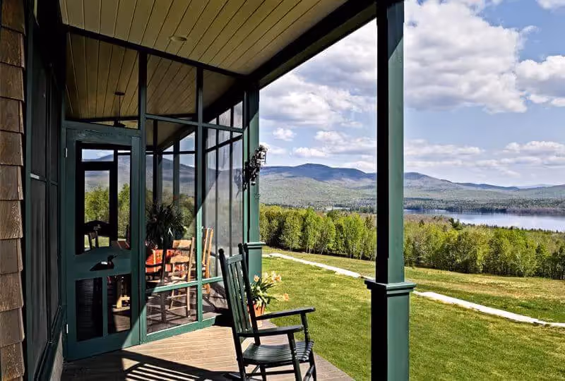 Peaceful porch with rocking chairs overlooking mountain lake and green landscape