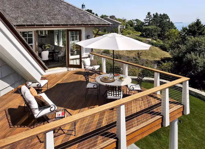 Wooden deck with white umbrella, outdoor furniture, and ocean view