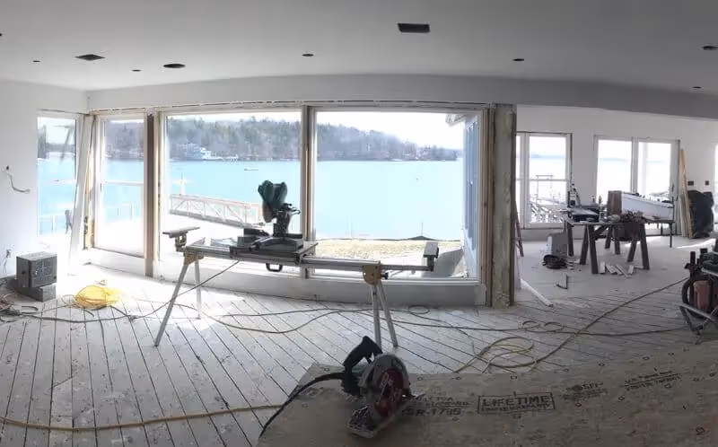 Unfinished interior with construction tools and lake view through large windows