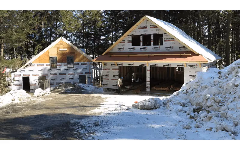 Wooden structures under construction in snowy forest with Tyvek house wrap