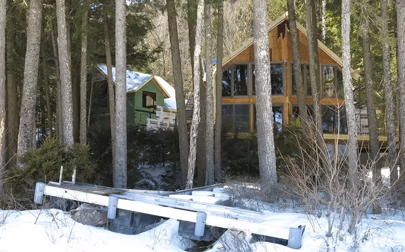 Wooden cabins in snowy forest with wooden walkway between trees