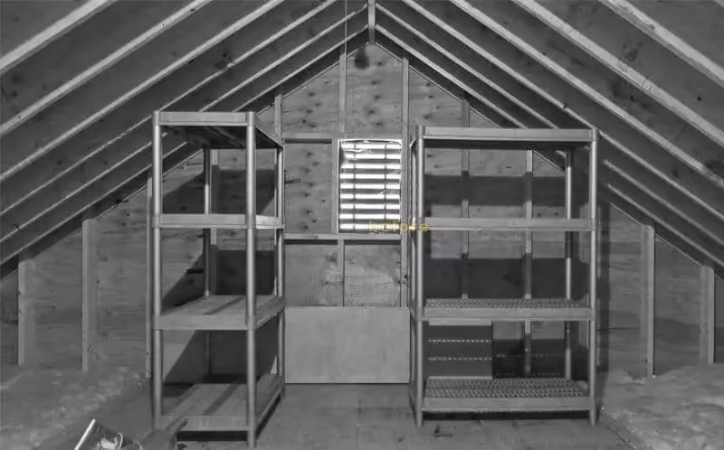 Wooden storage shelves inside an empty attic with angled roof beams