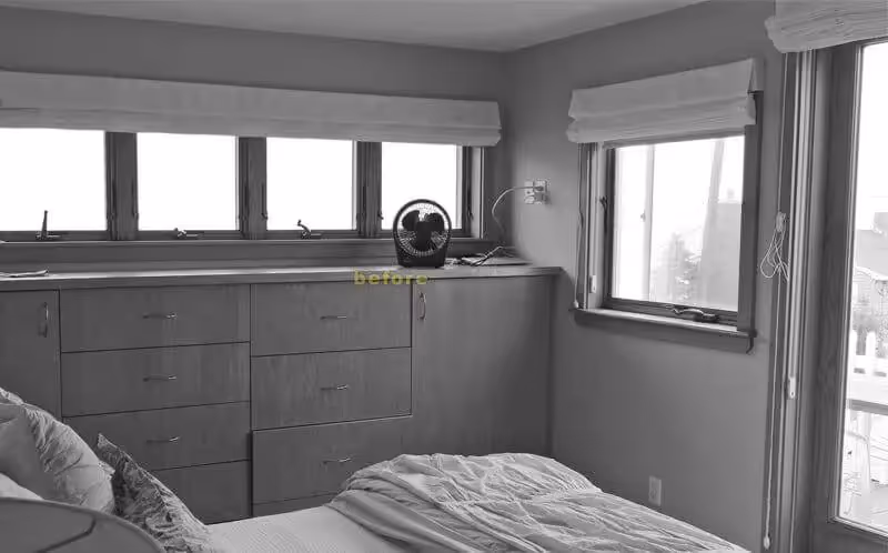 Bedroom interior with dresser, windows, and unmade bed in black and white