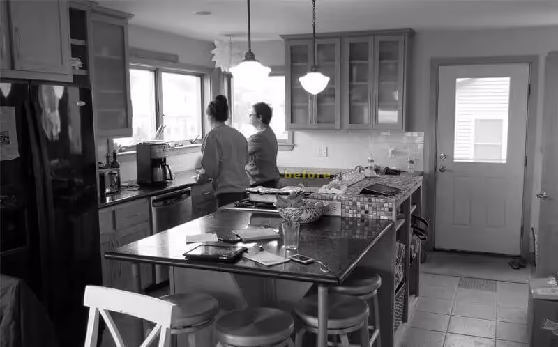 Two people standing in kitchen, viewed from behind near countertop