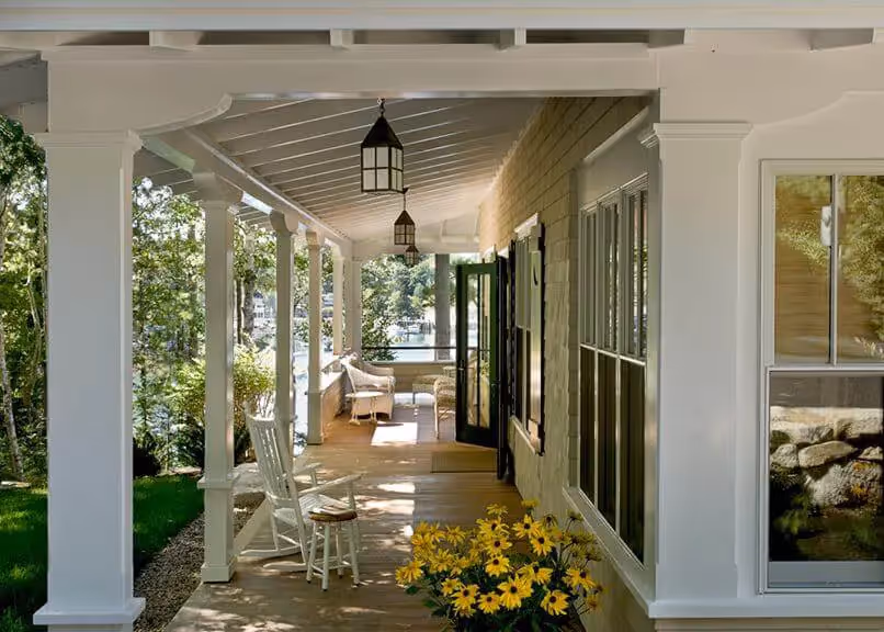 Sunny porch with white columns, rocking chairs, and yellow flowers