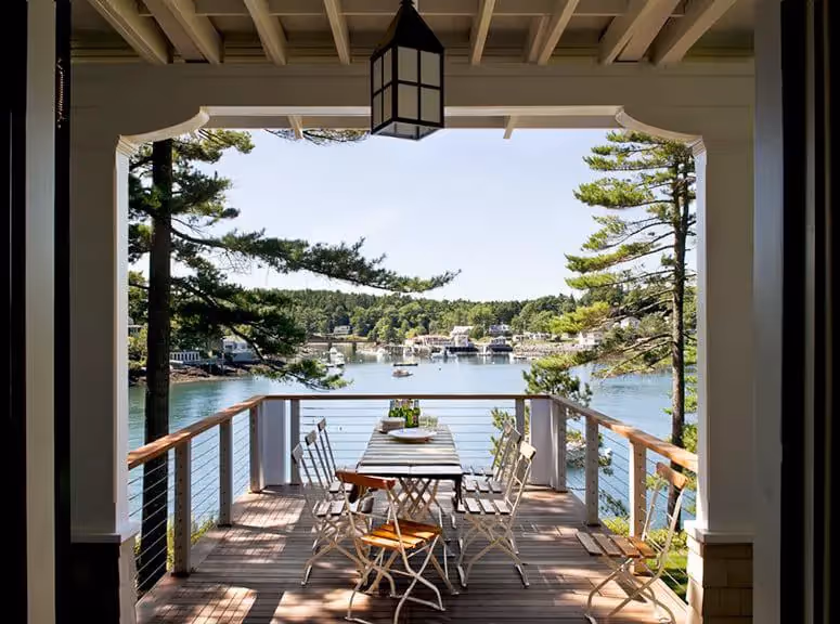 Outdoor deck overlooking serene harbor with boats and pine trees