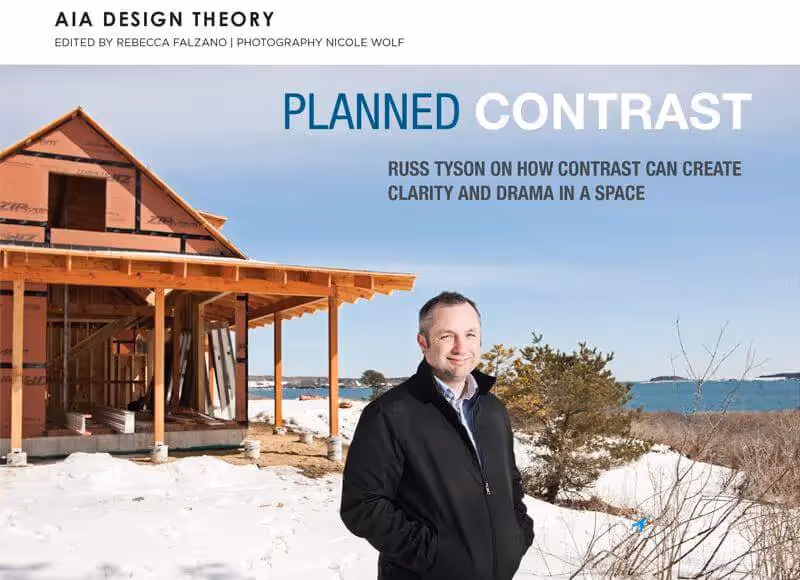 Architect standing near wooden structure by snowy coastline with ocean view