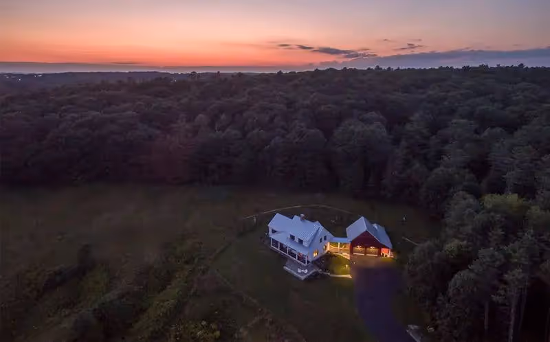 Glowing farmhouse nestled in forest at sunset with warm evening light