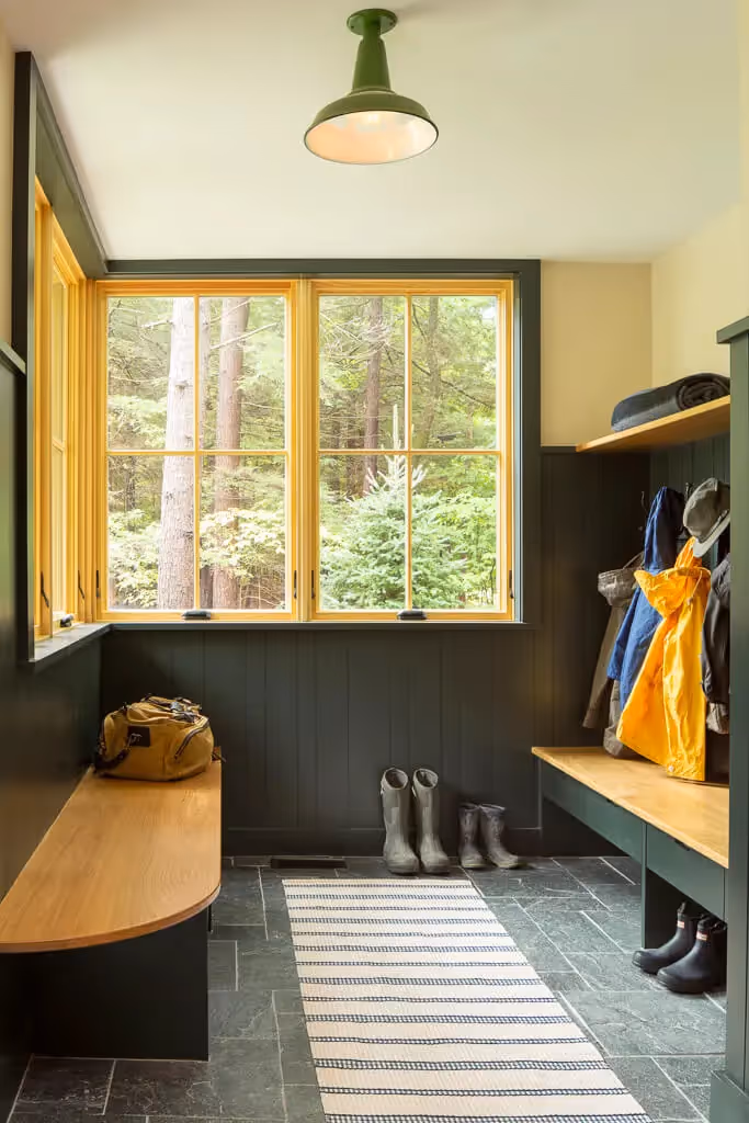 Mudroom with large windows, forest view, boots, and hanging jackets