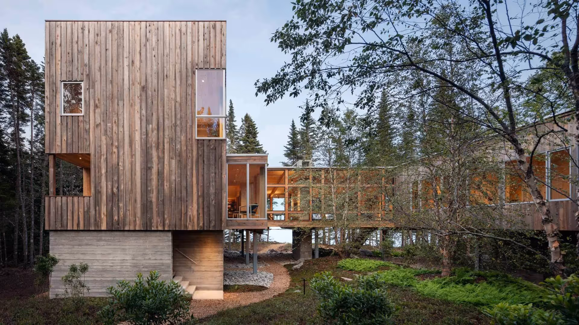 Modern wooden house on stilts nestled in forest with large windows