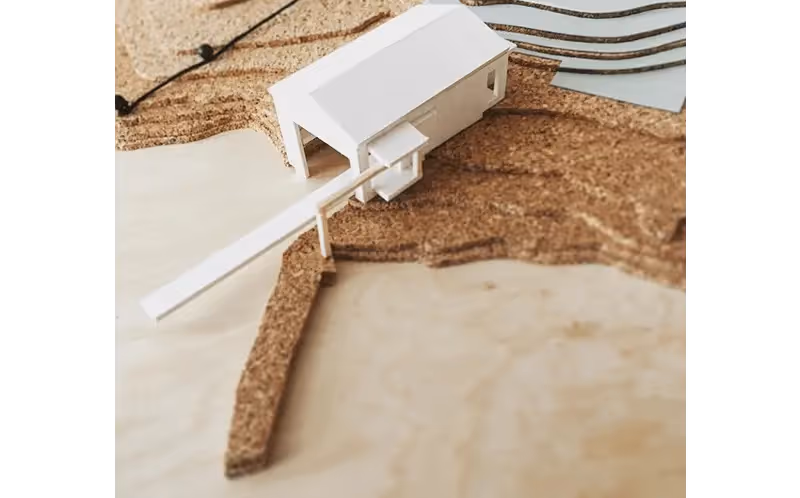 White architectural model house on textured beige background