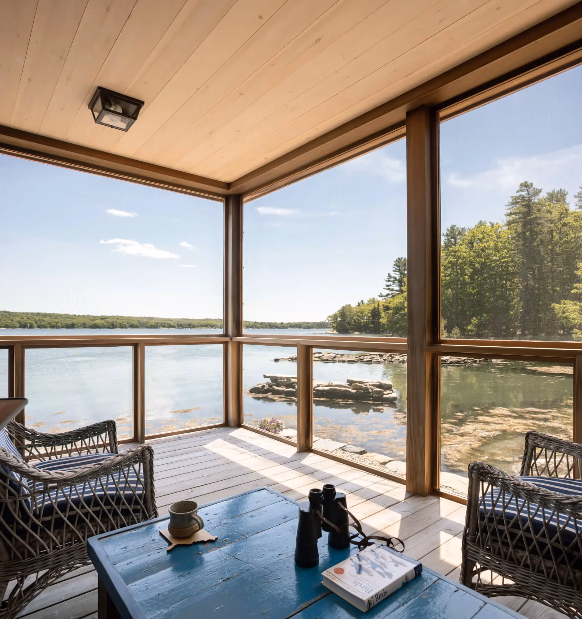 Lakeside porch with wicker chairs, scenic water and forest view