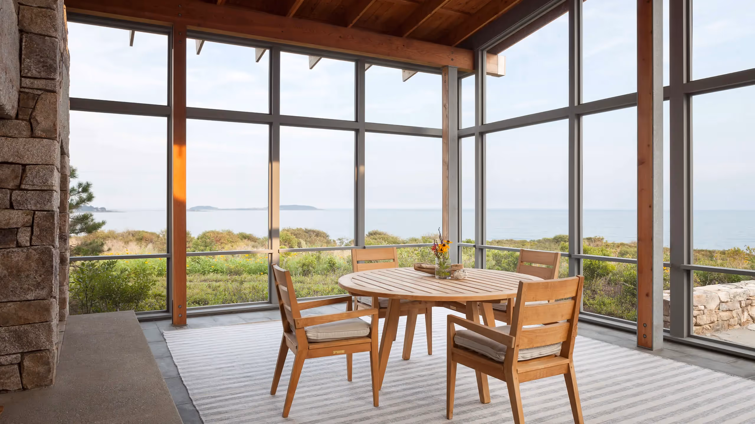 Dining area with ocean view through large windows in coastal home