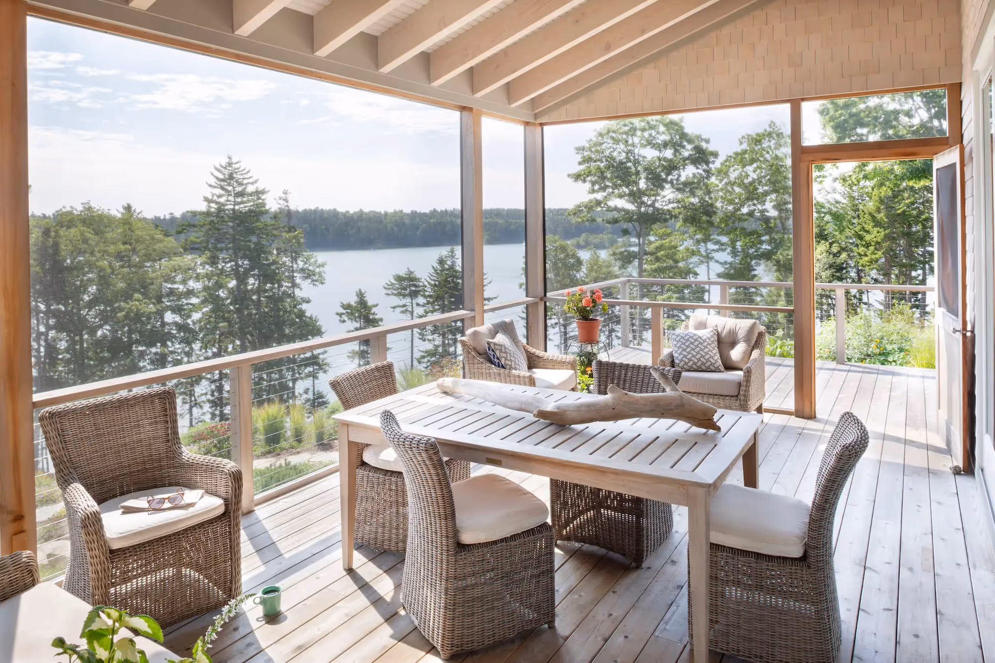Lakeside porch with wicker furniture and panoramic forest and water view
