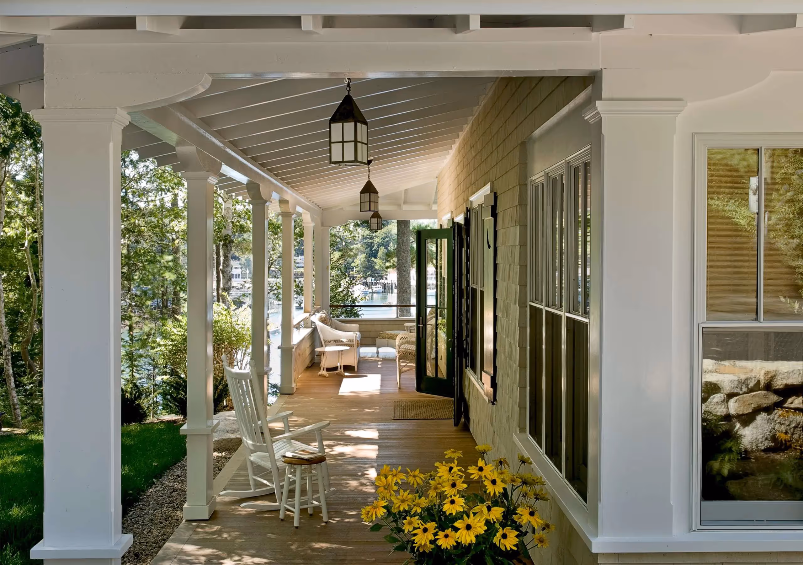 Sunlit covered porch with white rocking chair and yellow flowers