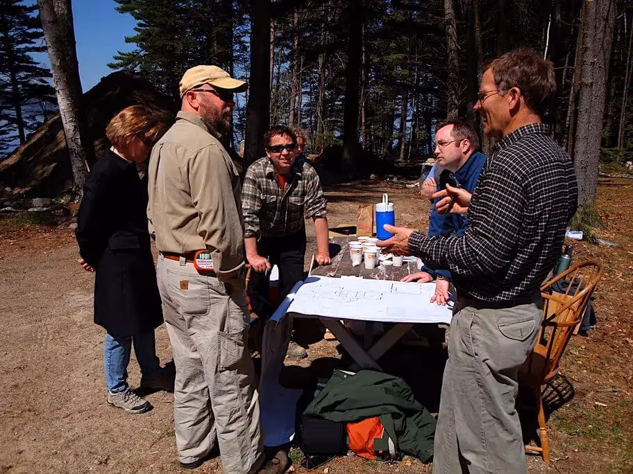 Group of researchers discussing project around table in forest setting