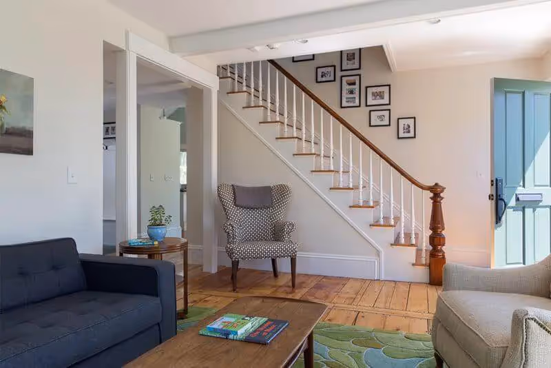Cozy living room with wooden floors, staircase, and framed artwork