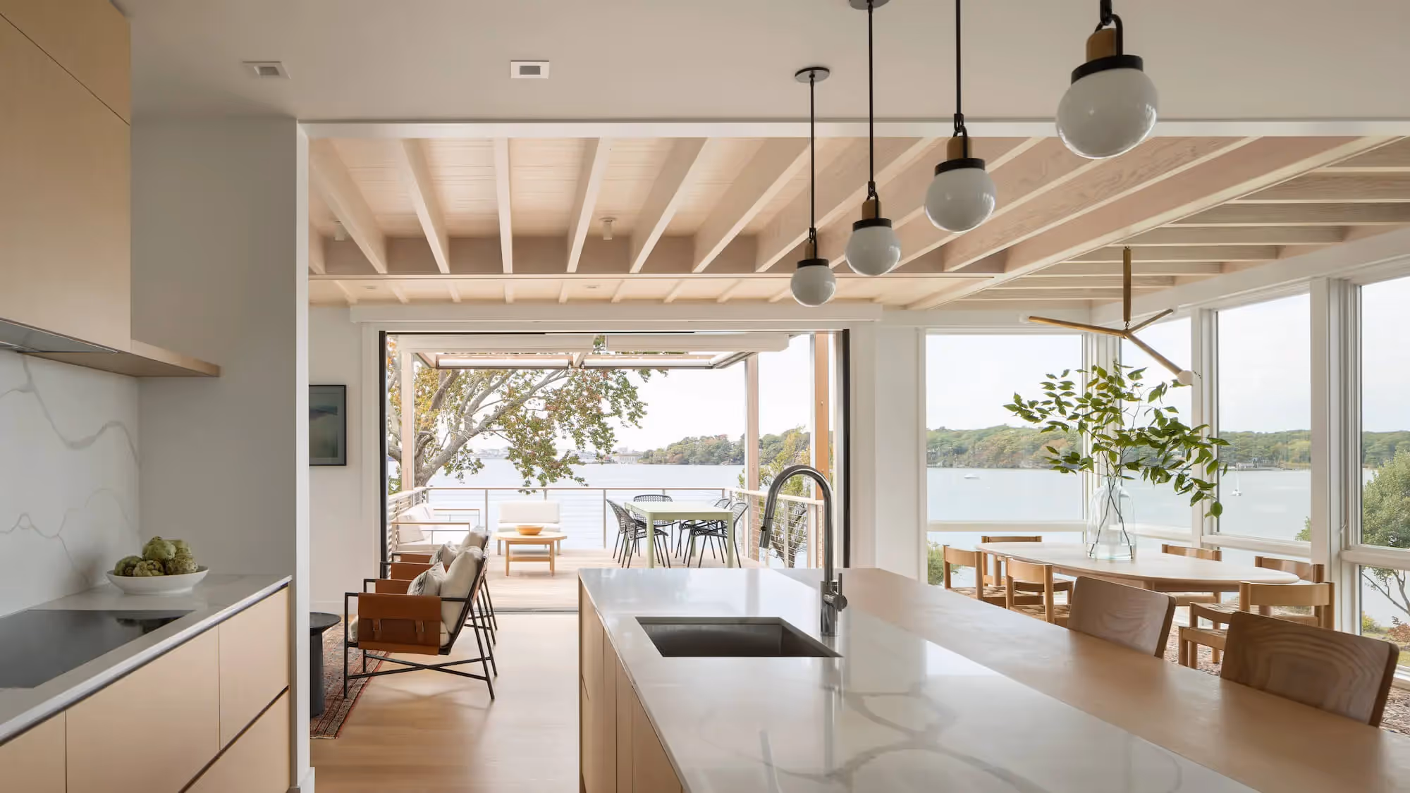 Modern kitchen with large windows overlooking water and open deck
