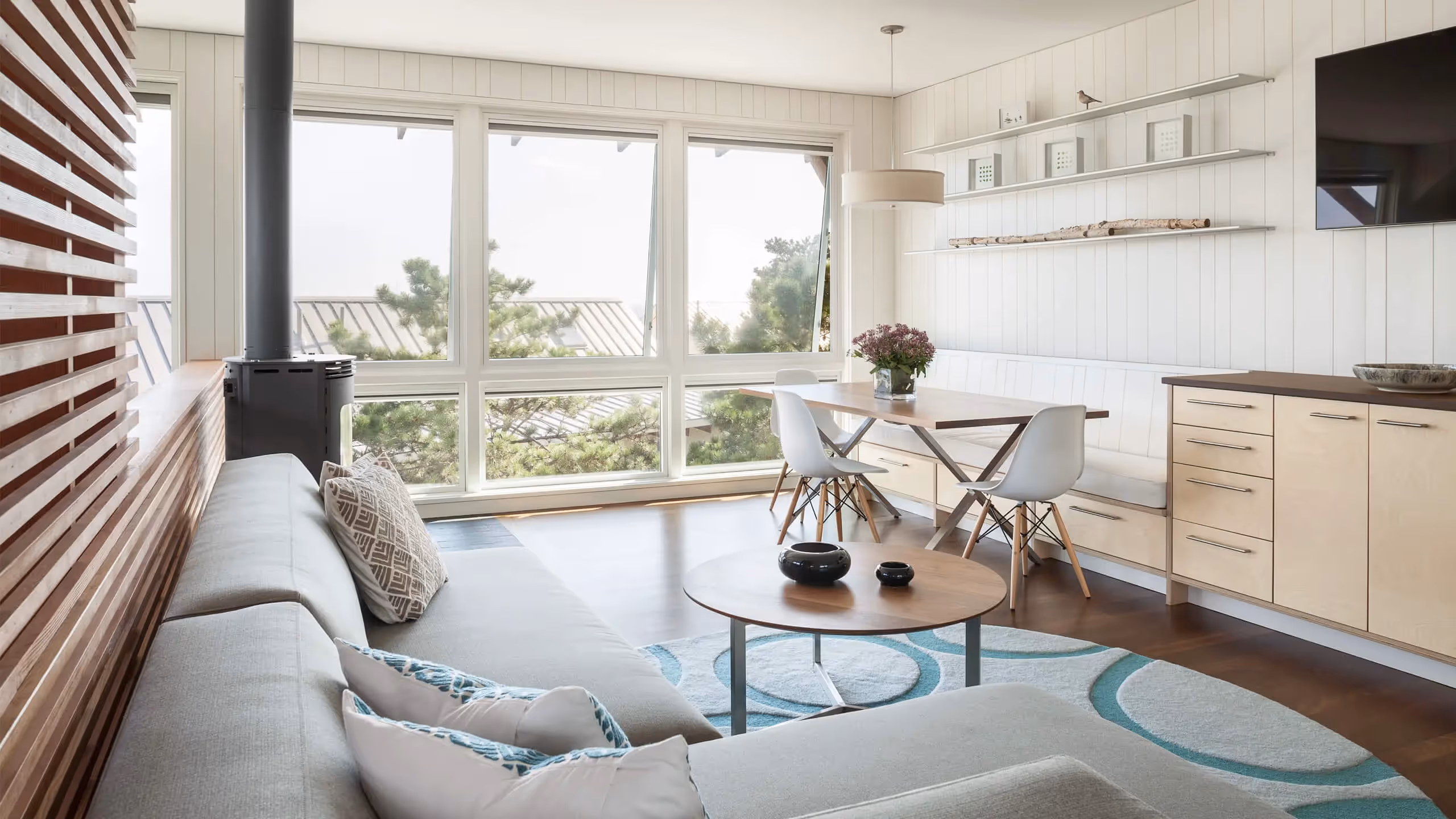 Modern living room with wood stove, large windows, and minimalist design