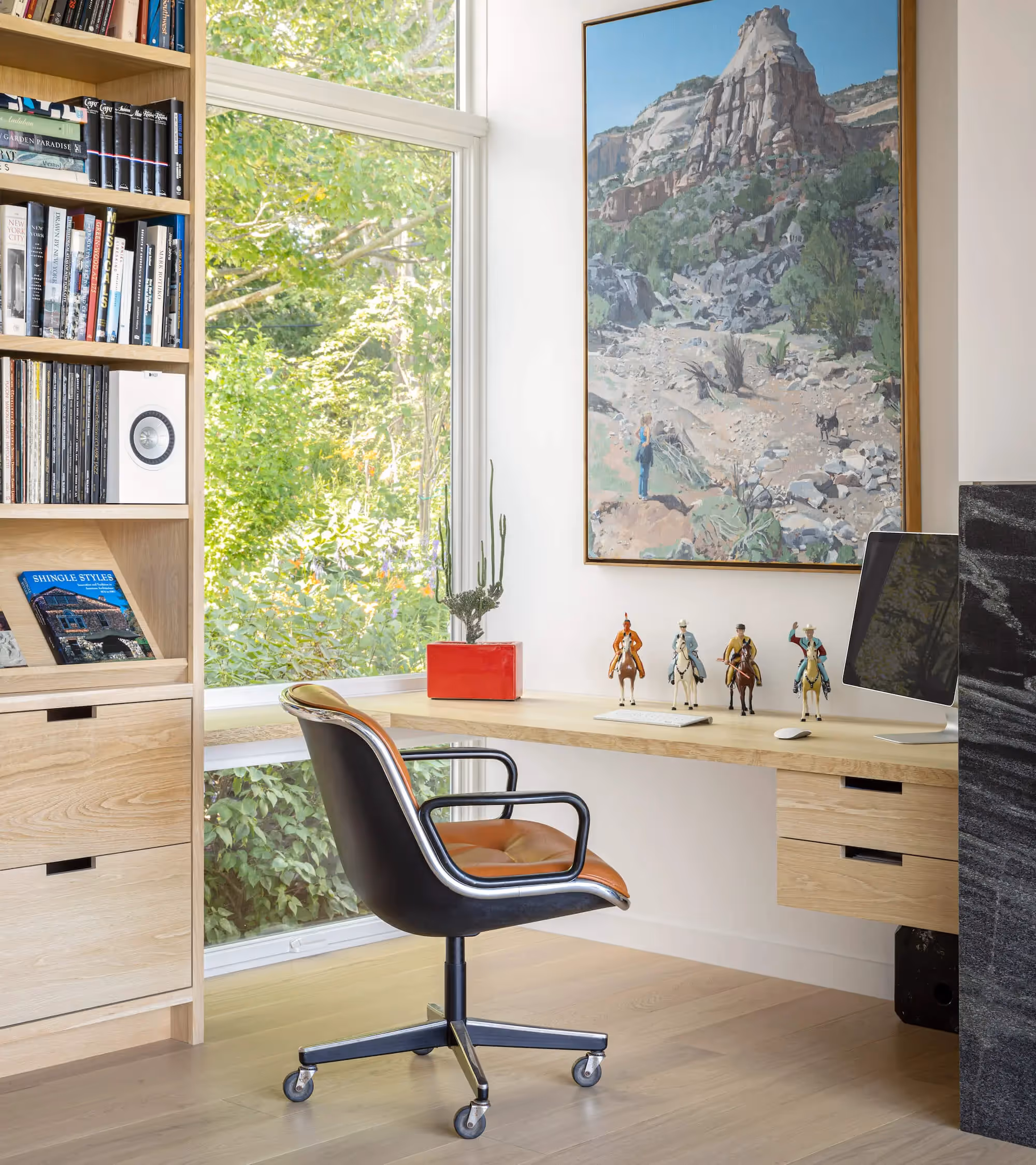 Modern home office with bookshelf, landscape painting, and horse figurines