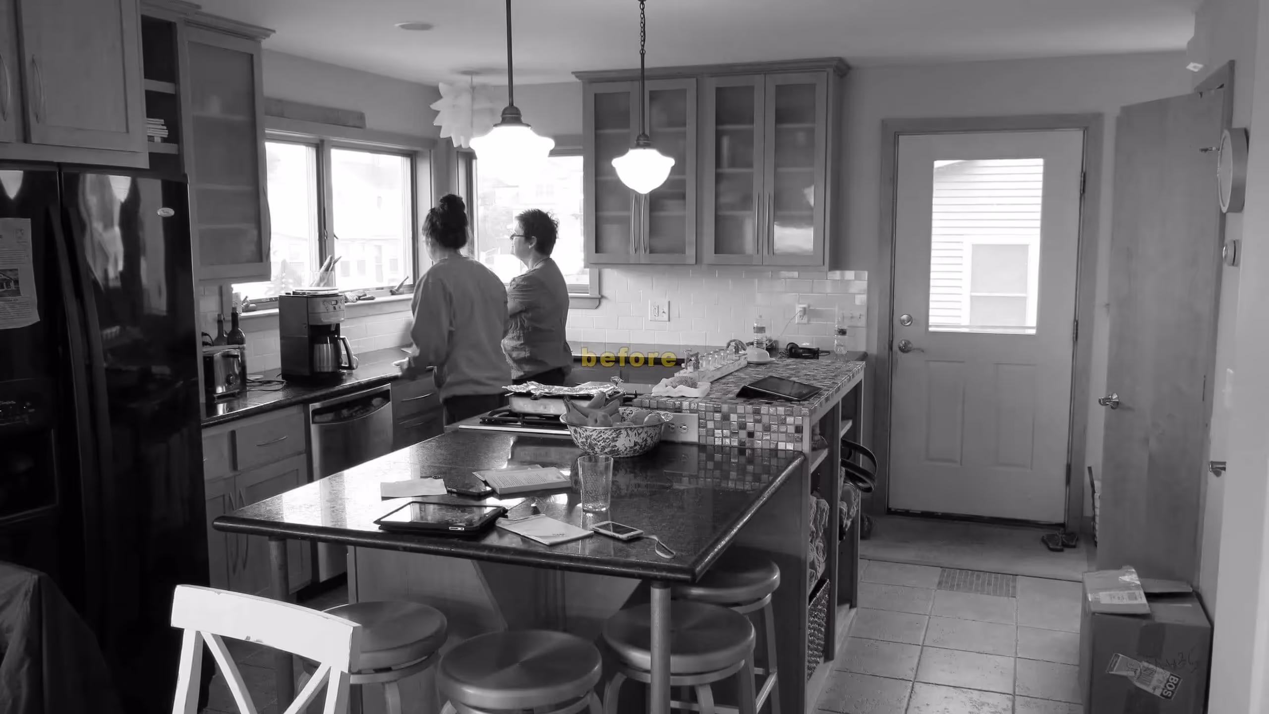 Two people in kitchen with island, black and white home interior