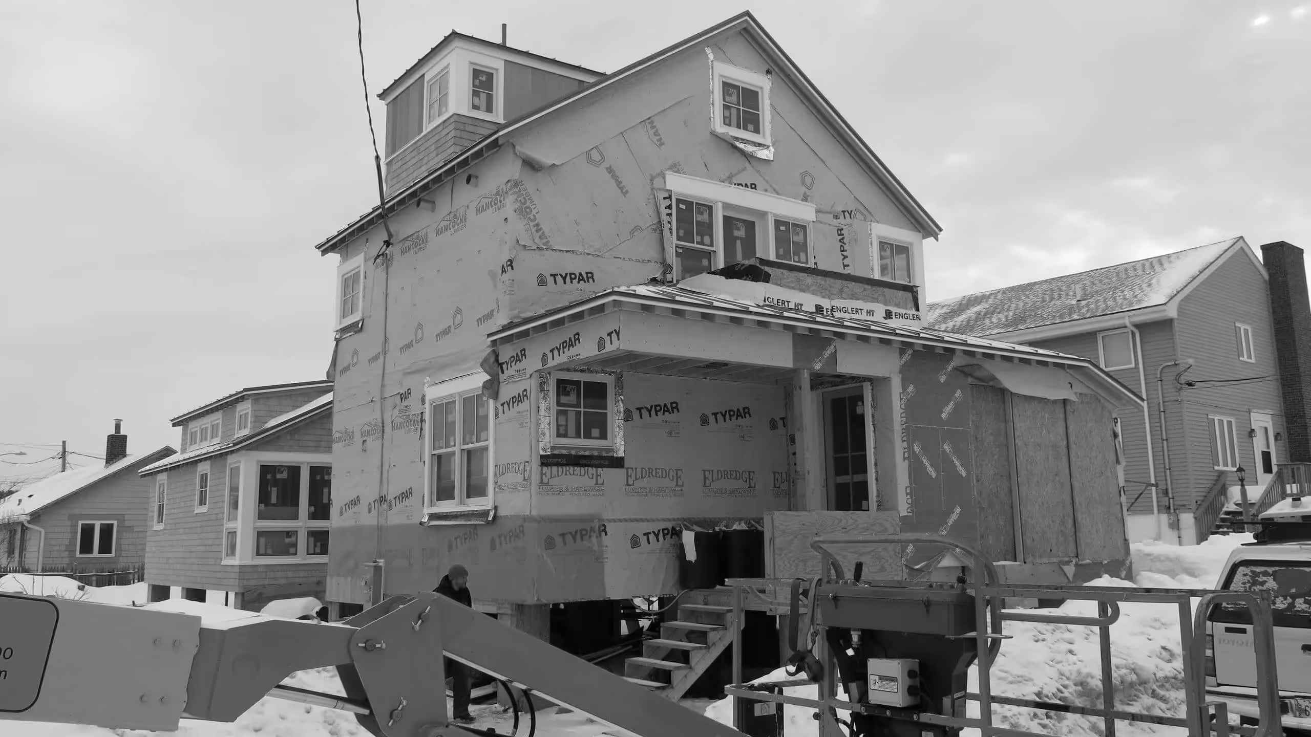House under construction in snowy neighborhood with building materials