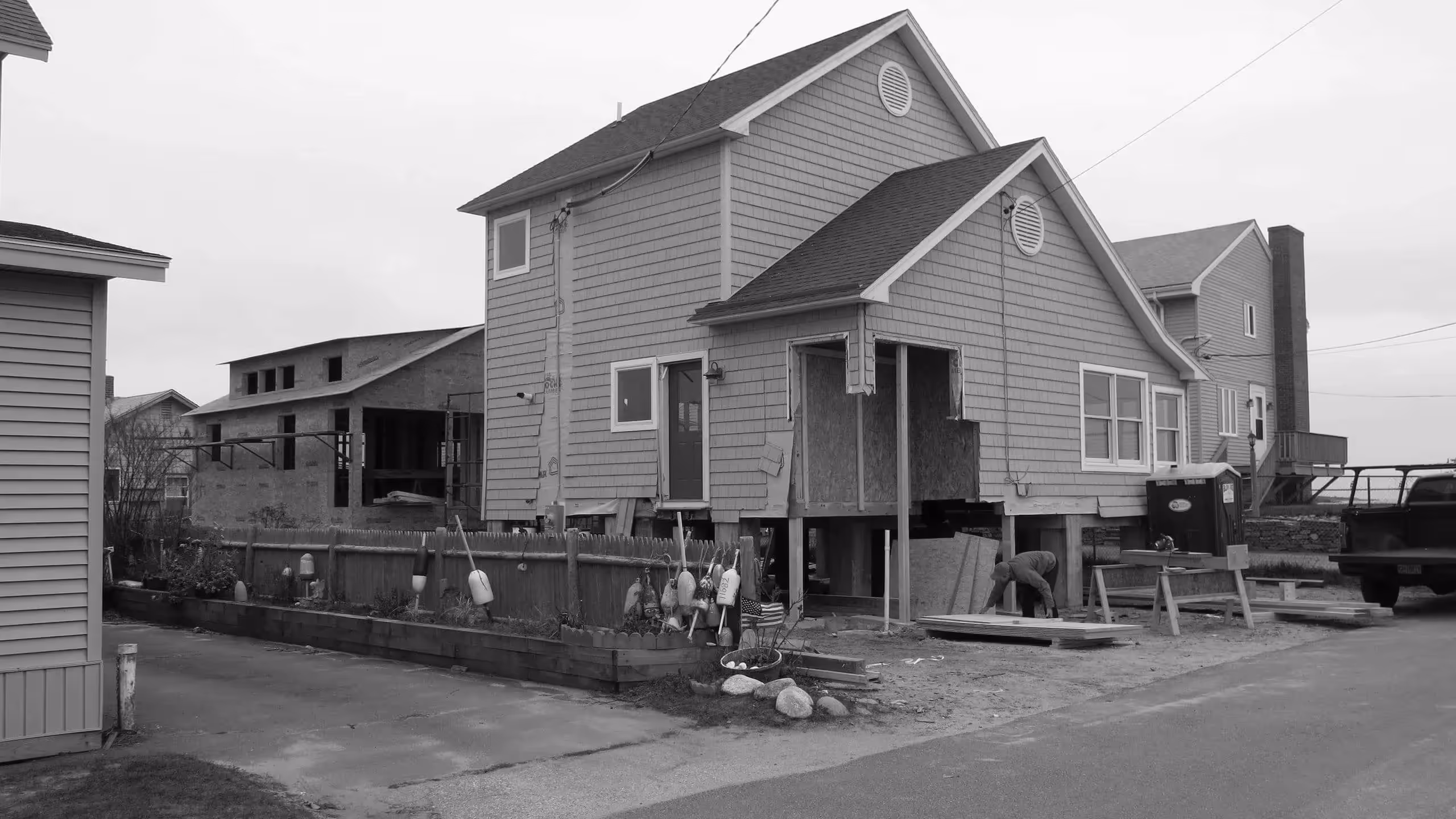 Coastal house under construction with wooden fence and construction materials