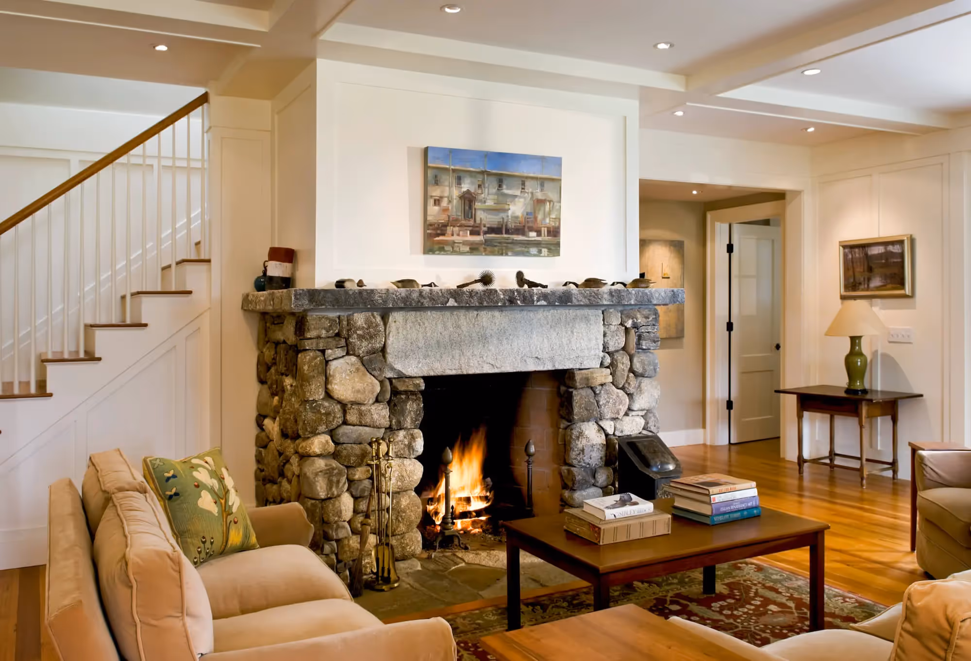 Cozy living room with stone fireplace burning, warm wooden floors, comfortable furniture