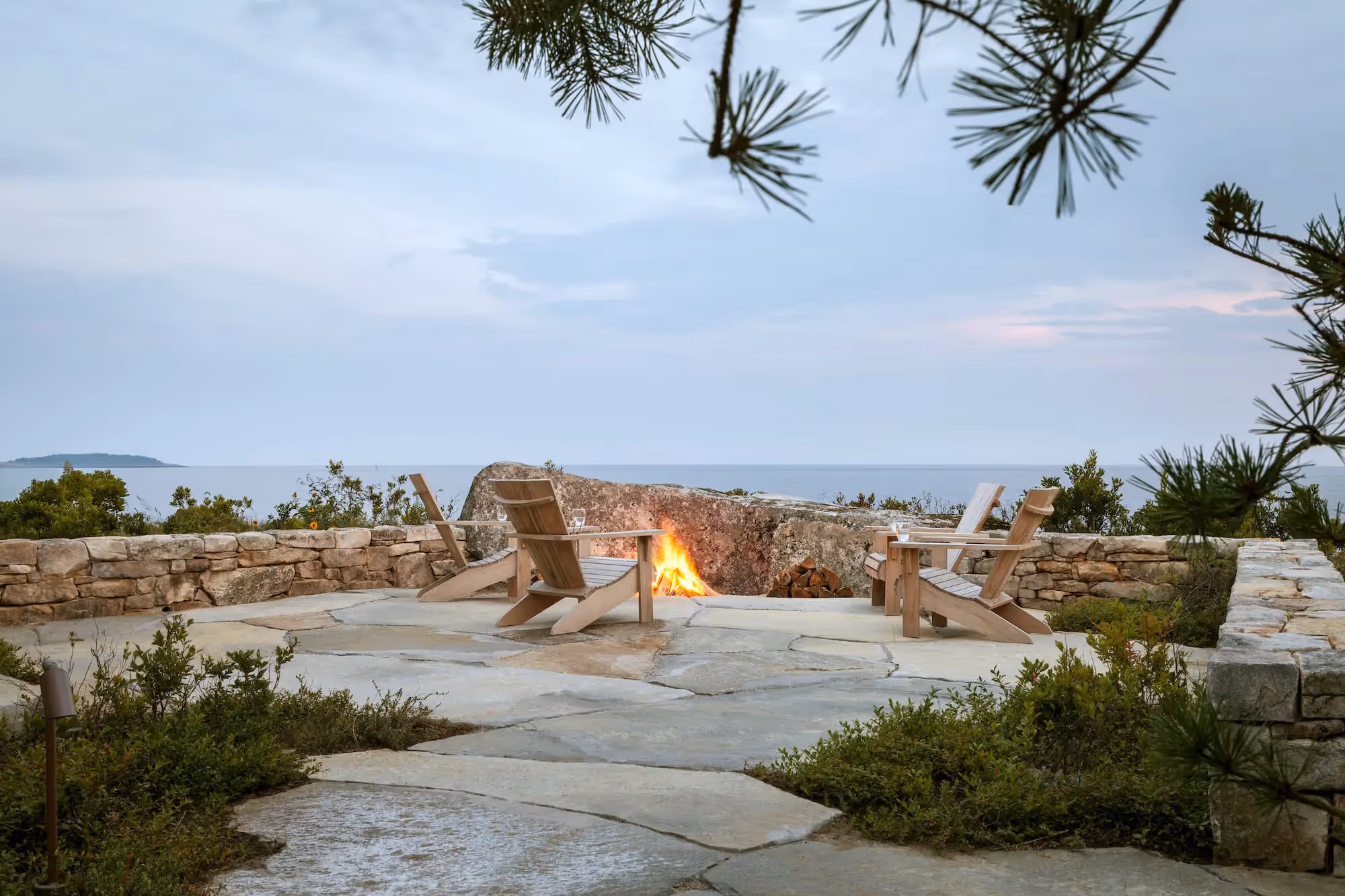 Coastal fire pit with Adirondack chairs overlooking calm ocean view