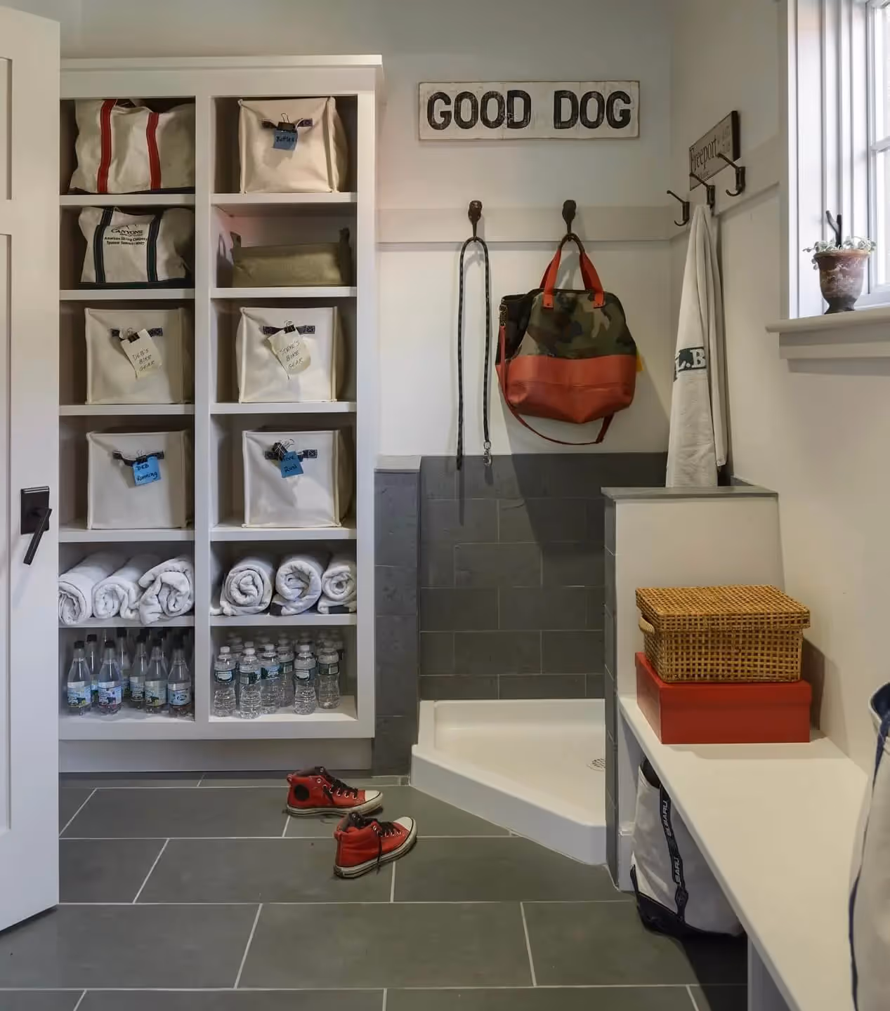 Organized mudroom with shelves, water bottles, bags, shoes, and "Good Dog" sign