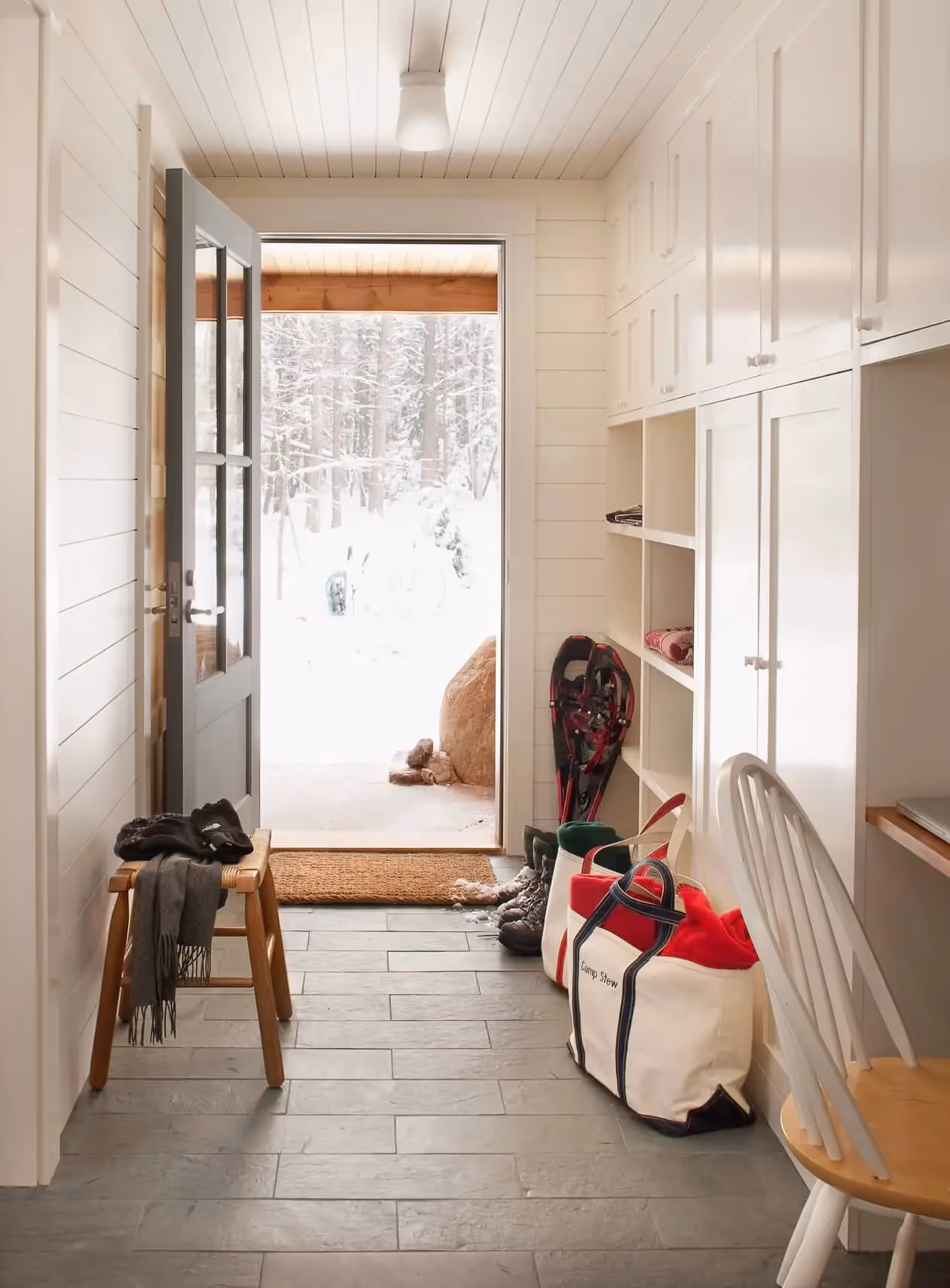 Mudroom with open door revealing snowy winter forest landscape