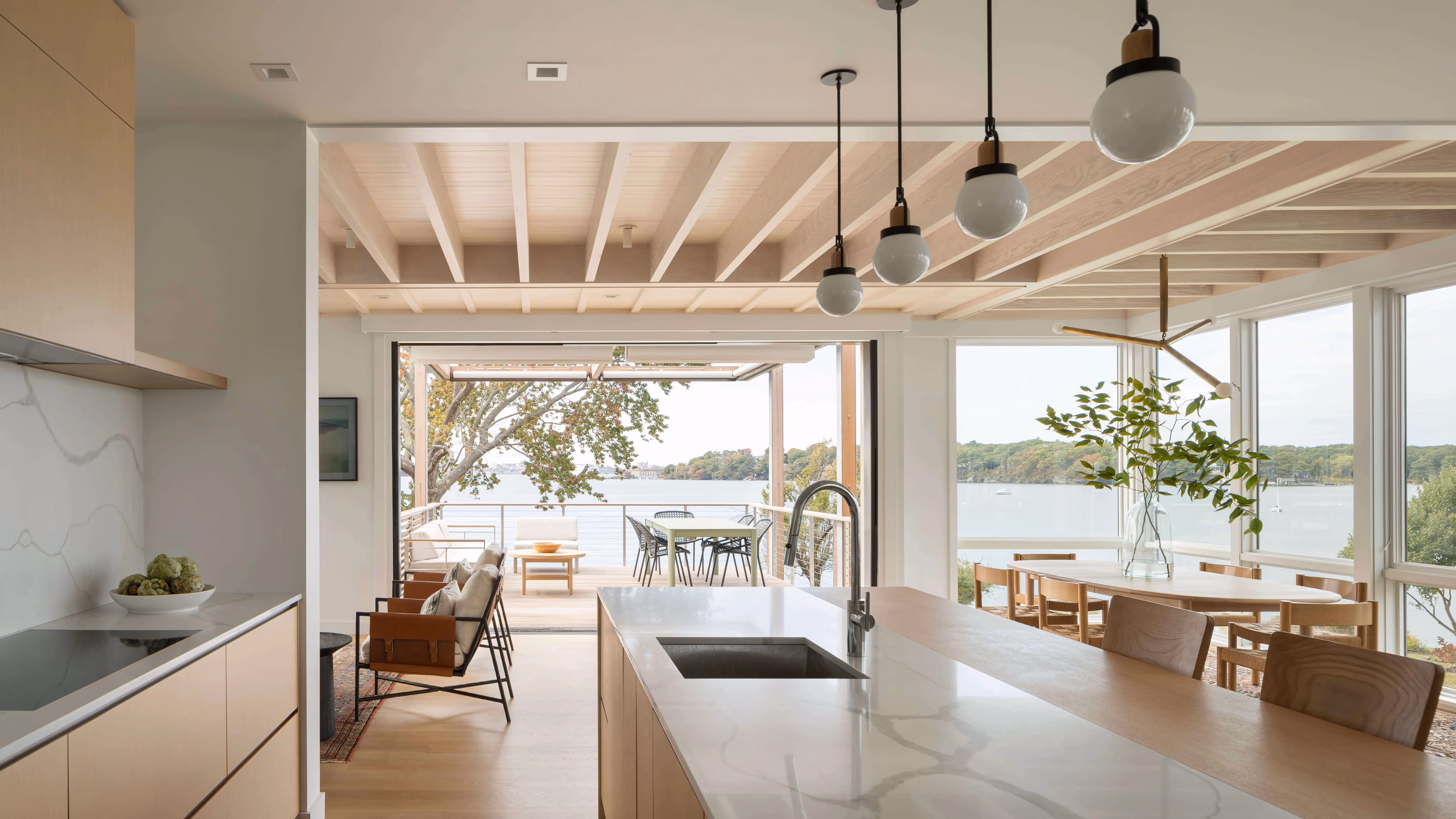 Modern kitchen with waterfront view, open design, and hanging globe lights
