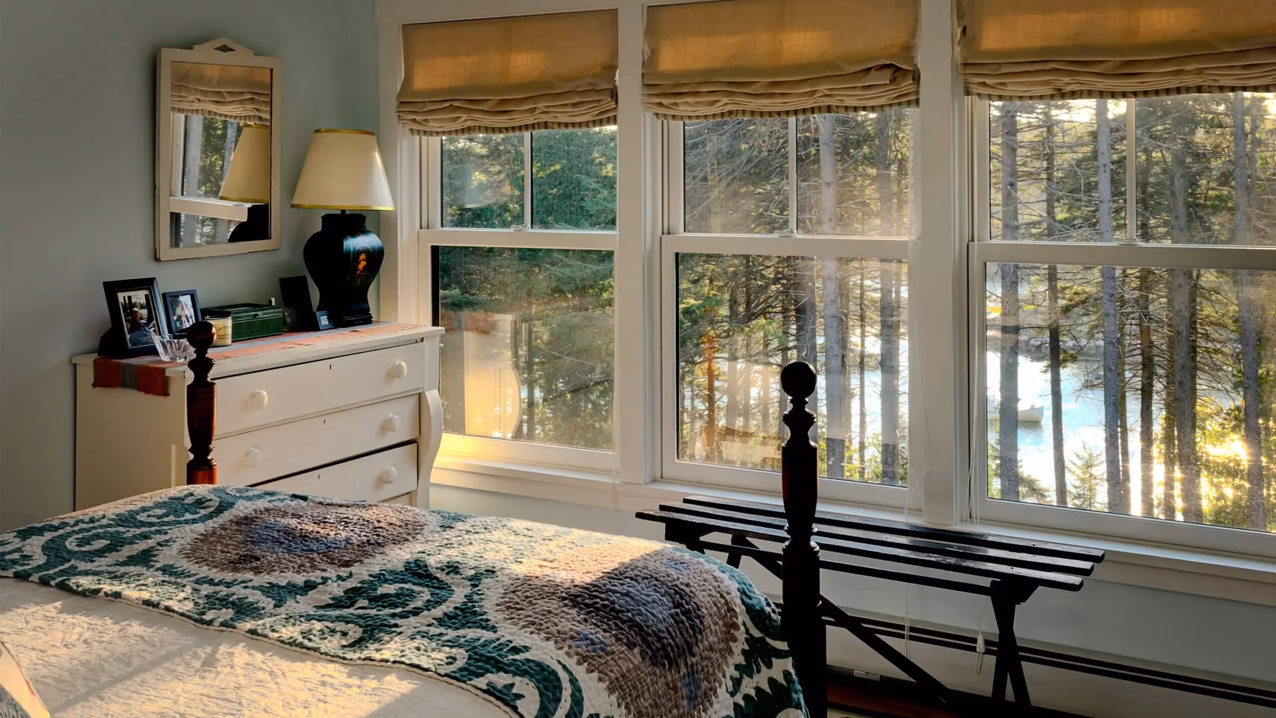Cozy bedroom with forest view through large windows, patterned bedspread