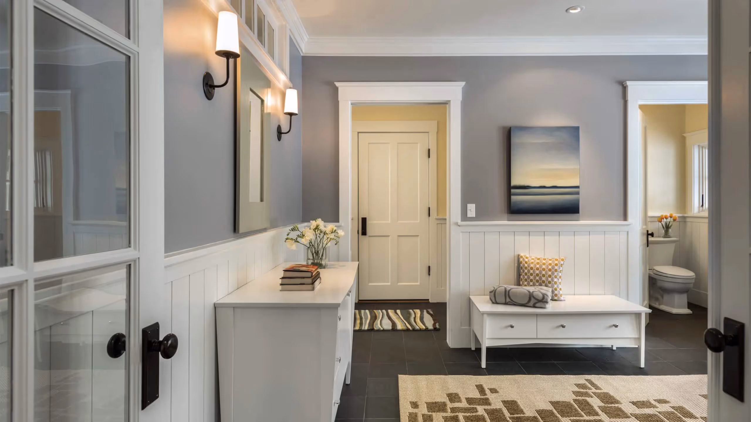 Elegant entryway with white wainscoting, gray walls, and stylish decor