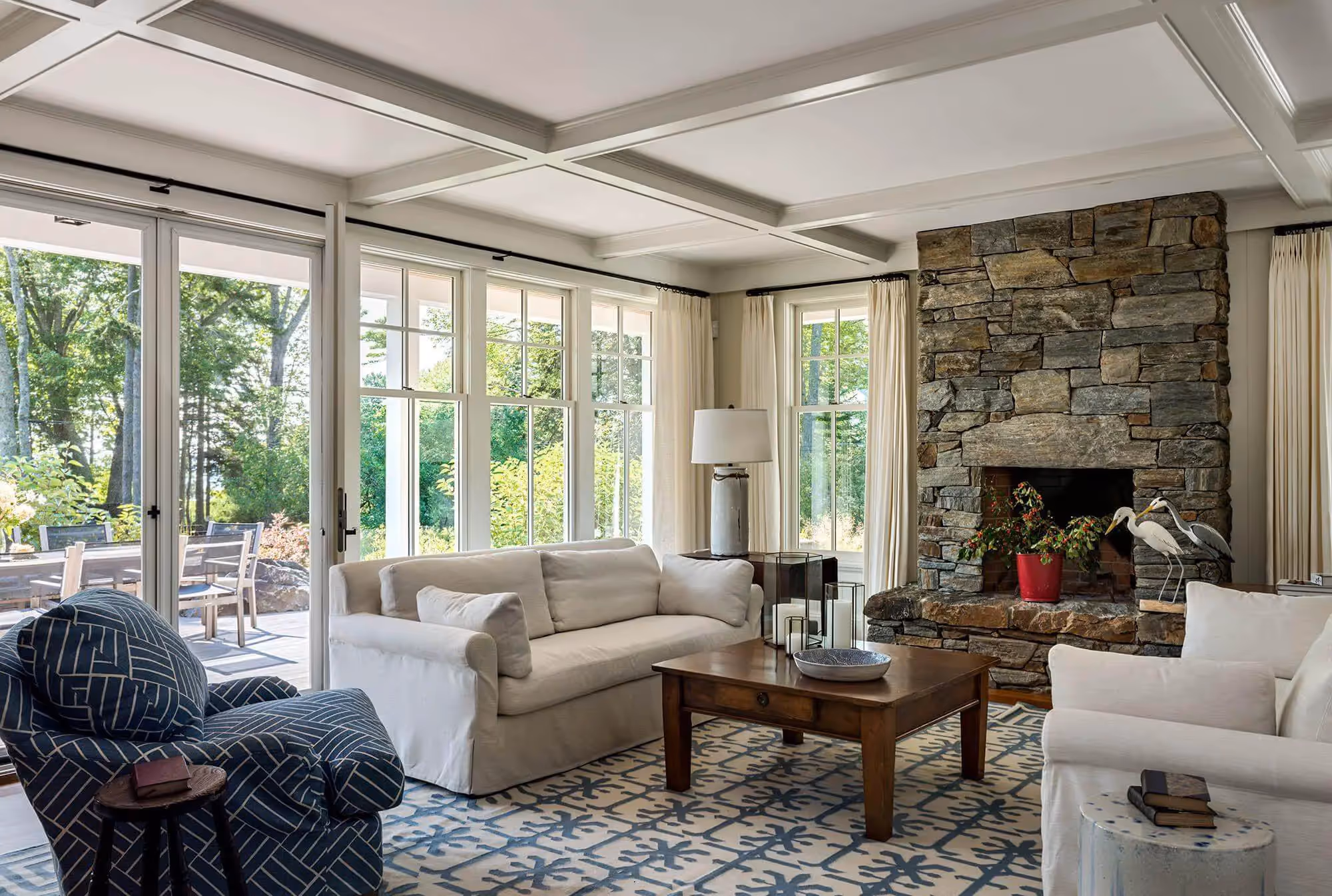 Bright living room with stone fireplace, white sofas, and large windows