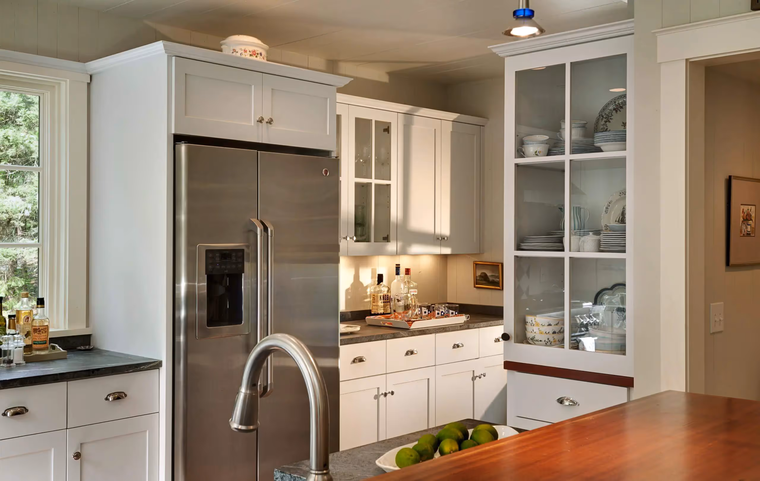 White kitchen with stainless steel appliances, wood countertop, and green limes