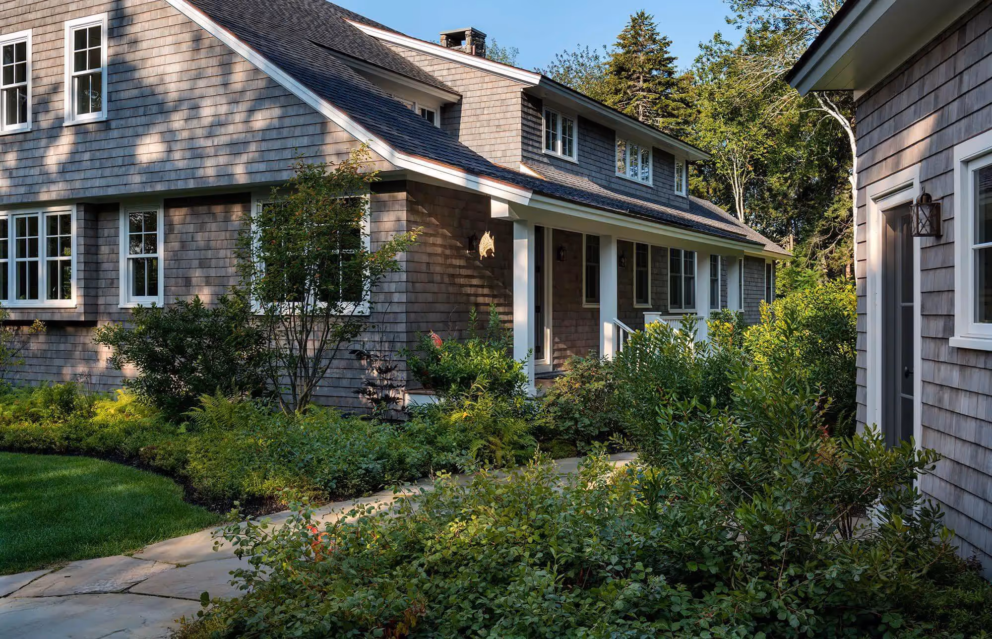 Shingle-style beach house with lush gardens and stone walkway