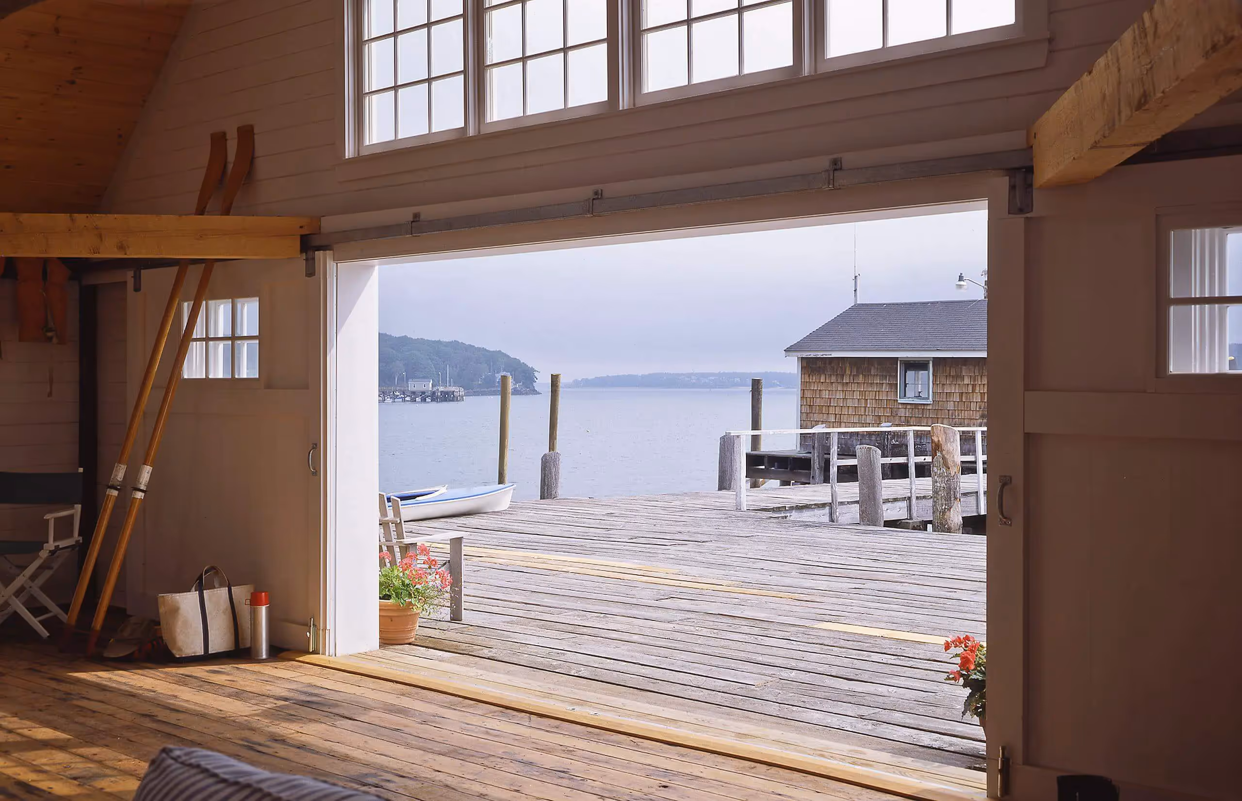 Wooden boathouse interior with view of dock, boats, and calm water