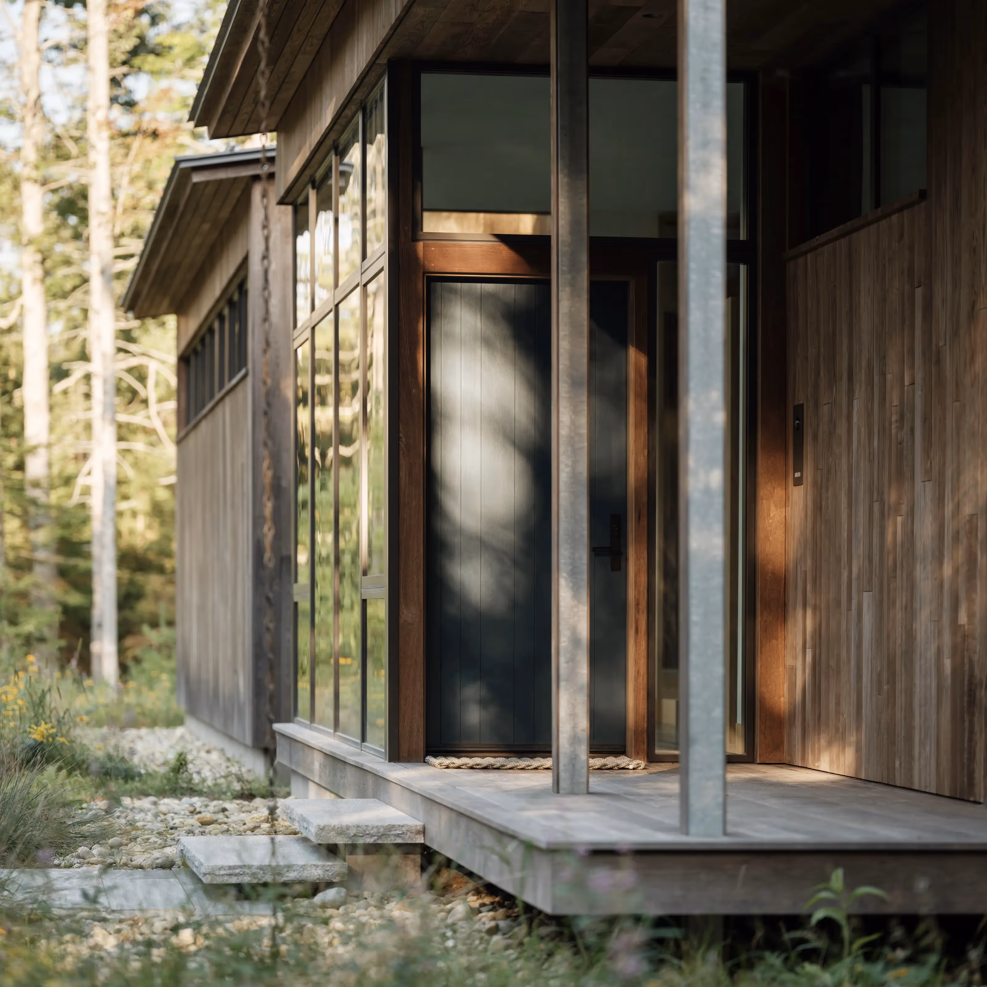 Wooden cabin with large windows nestled in a forest setting