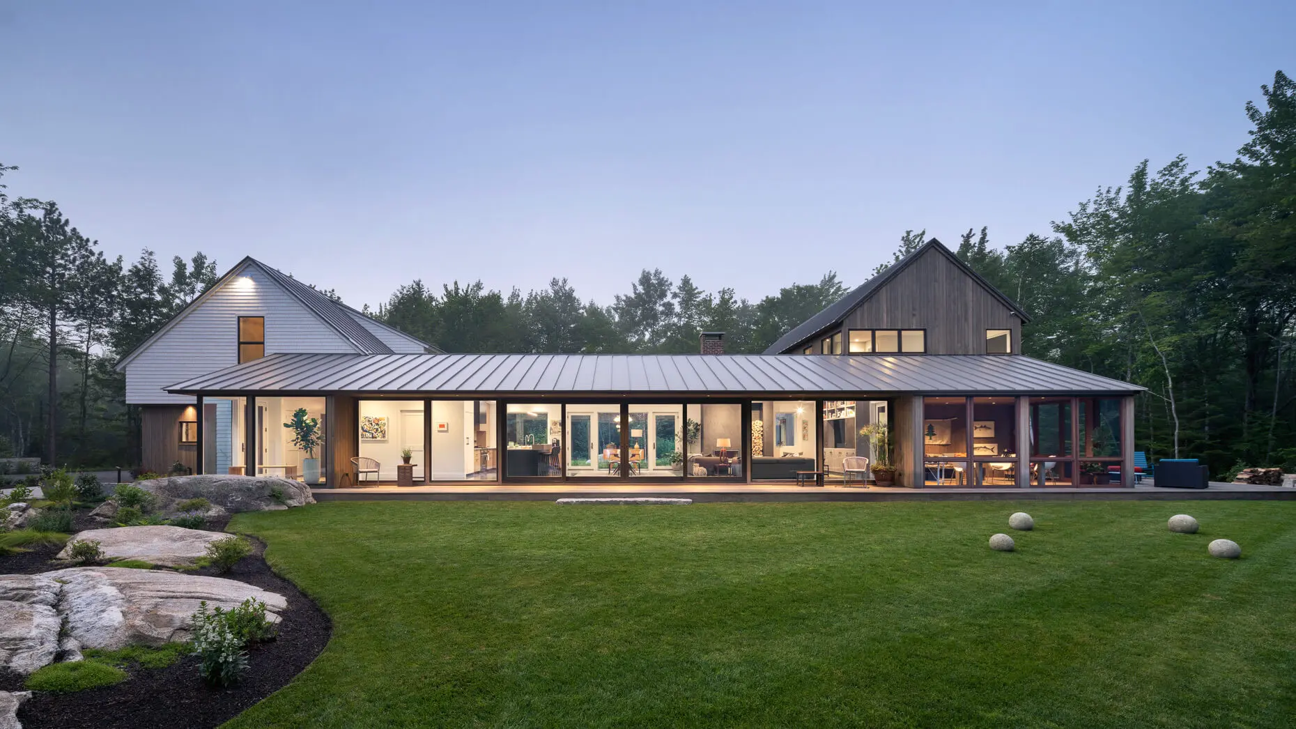 Modern wooden house with large windows nestled in forested landscape